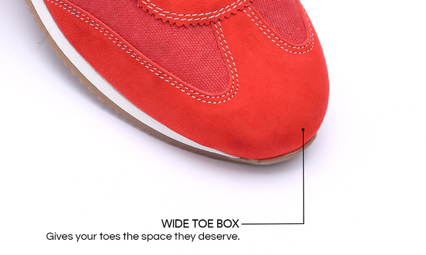 Close-up of a red sneaker showing the wide toe box with a callout line and text reading 'WIDE TOE BOX' and 'Gives your toes the space they deserve.' on a white background.